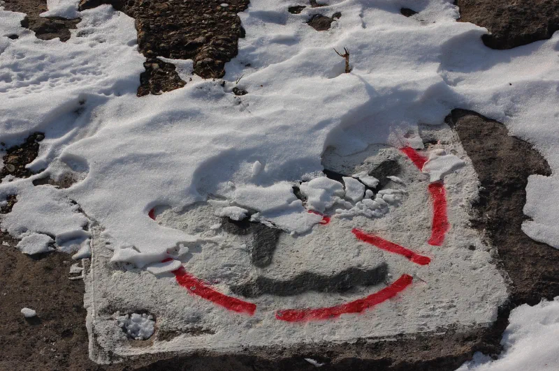 A red painted smiley face on a slab, half covered in snow